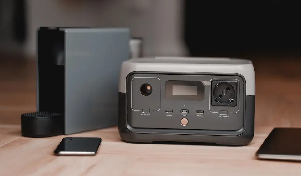 Portable power station on the floor beside other devices.