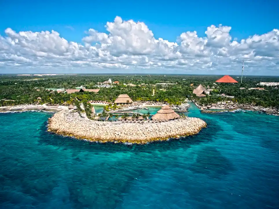 Aerial view of Xcaret park coastline with macaws flying over the water